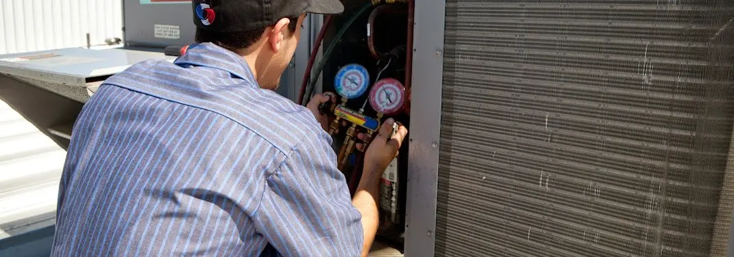 HVAC technician servicing a condenser unit in Galloway